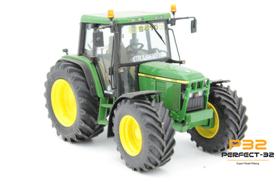 Model green tractor with large wheels on a white background