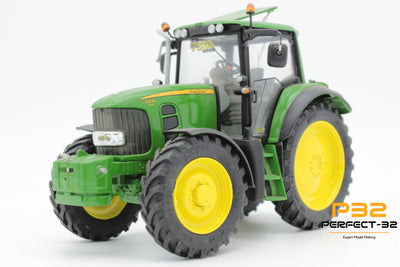 Model of a green tractor with yellow wheels on a white background