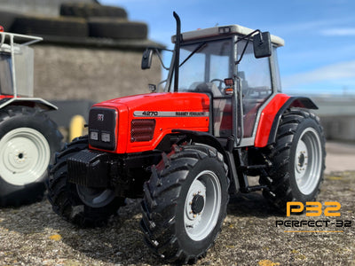 Red tractor on a concrete surface with a building and blue sky in the background